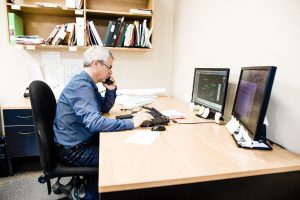 Homme au téléphone devant un écran d'ordinateur assis à un bureau