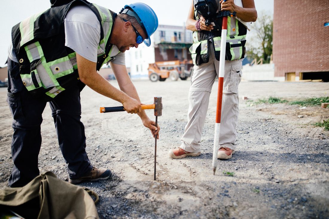 Arpenteurs implantant un repère sur un chantier de construction